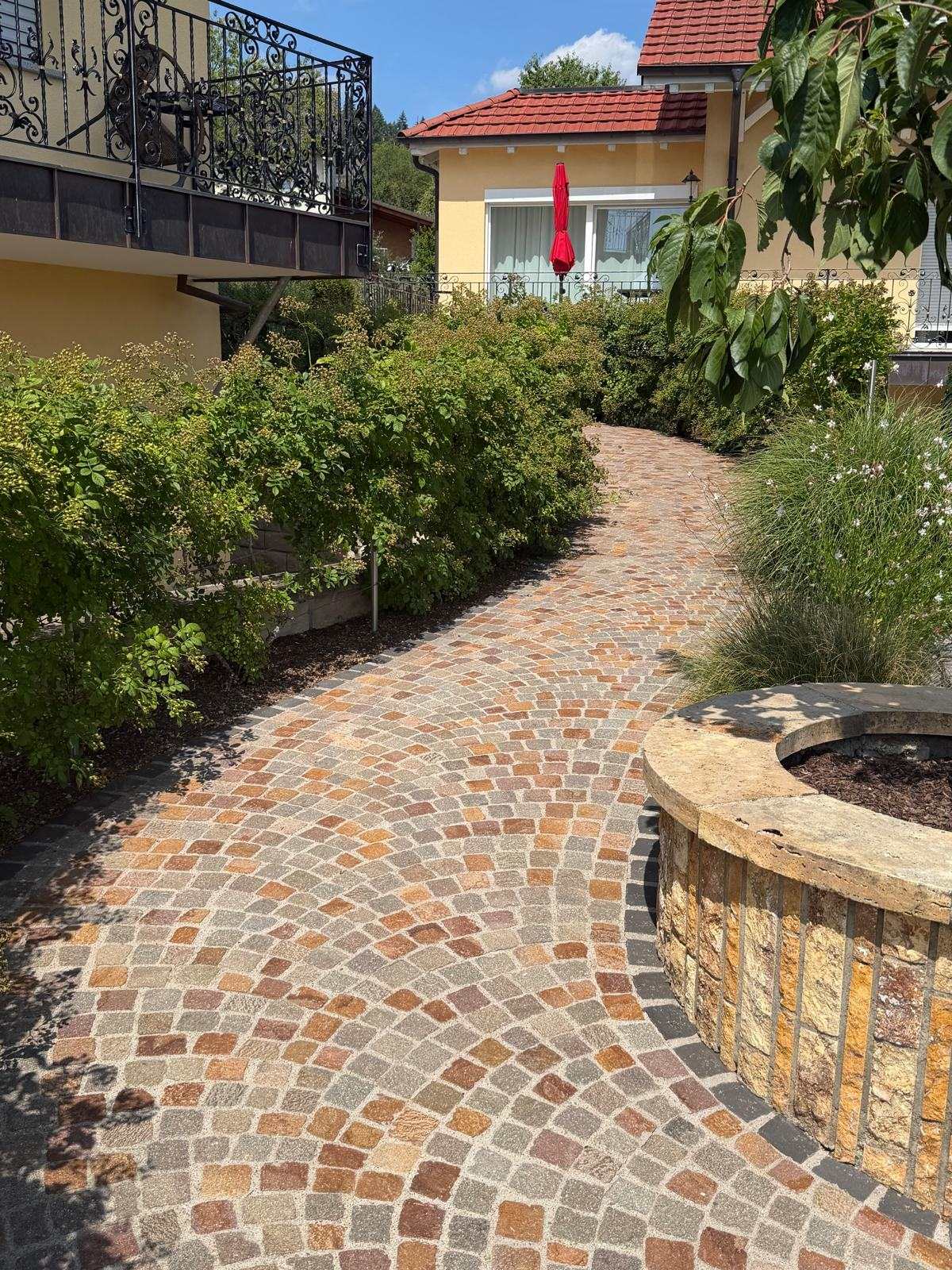 Gepflasterter Gartenweg mit rotem Sonnenschirm