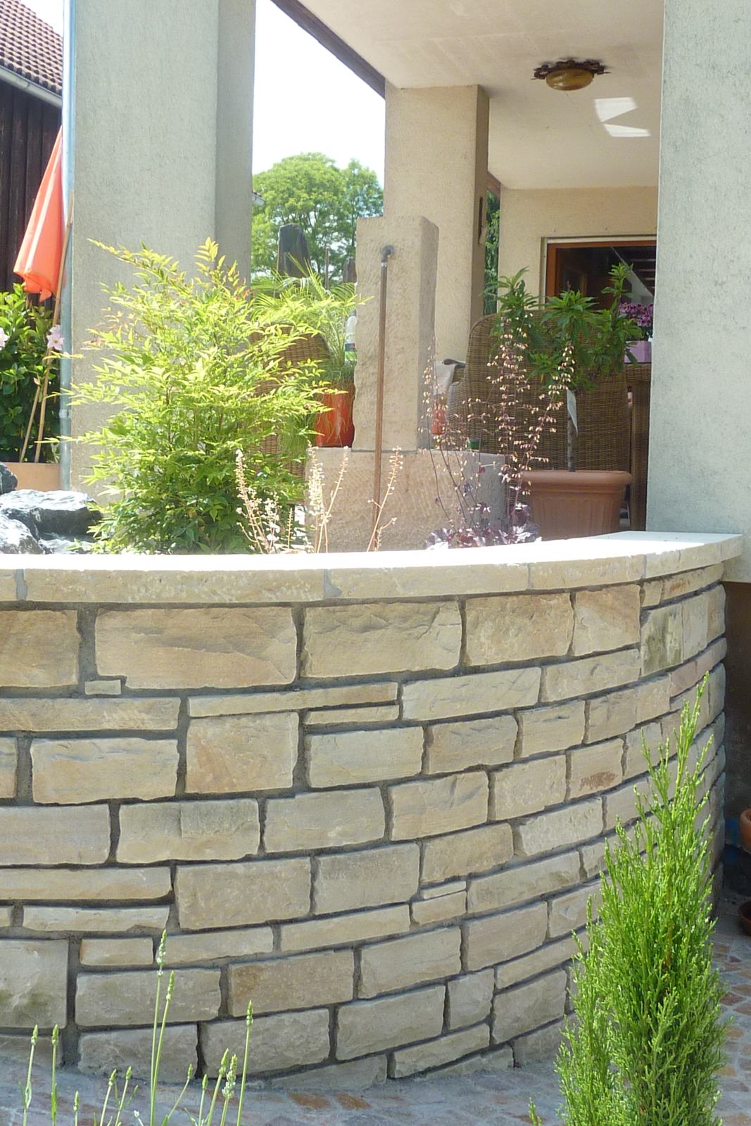 Geschwungene Natursteinmauer auf der Terrasse