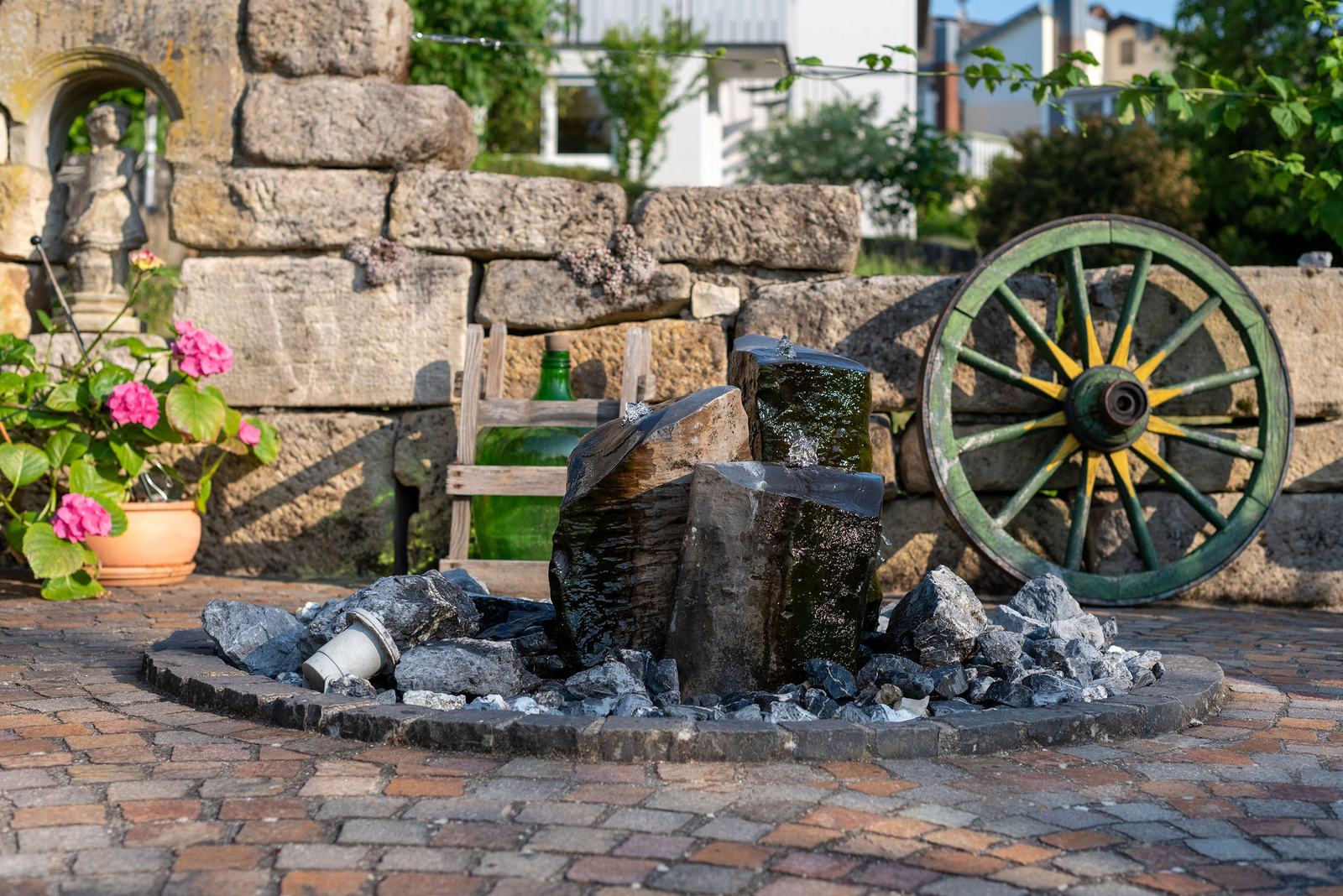 Schwarzer Natursteinbrunnen im Schaugarten